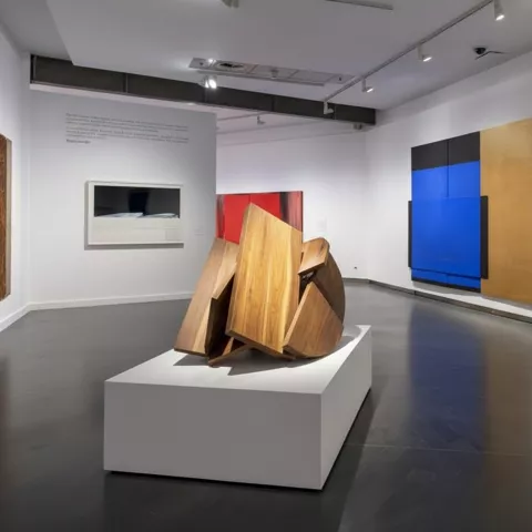 Espacio de arte moderno con escultura central y composiciones geométricas en pared.