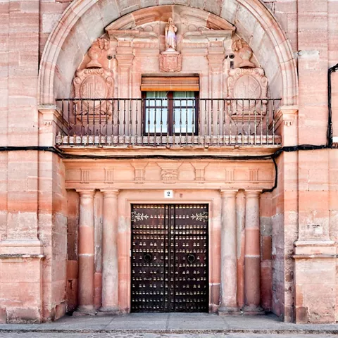 Fachada de piedra con balcón y gran portada ornamentada