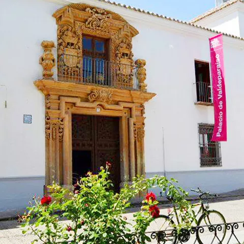 Vista general de palacio histórico de fachada blanca con portada barroca de piedra.