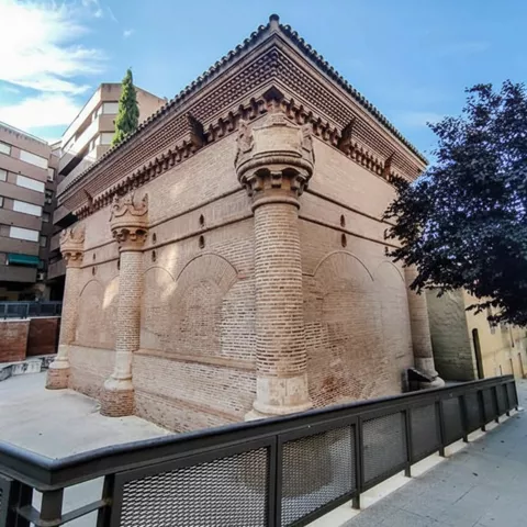 Vista lateral del edificio de ladrillo con columnas y arcos ciegos.