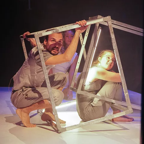 Intérpretes escénicos dentro de estructuras metálicas sobre escenario.