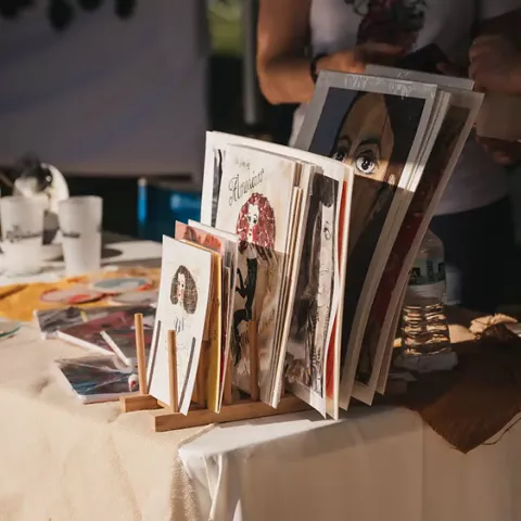 Mesa con ilustraciones y láminas artísticas expuestas para la venta.