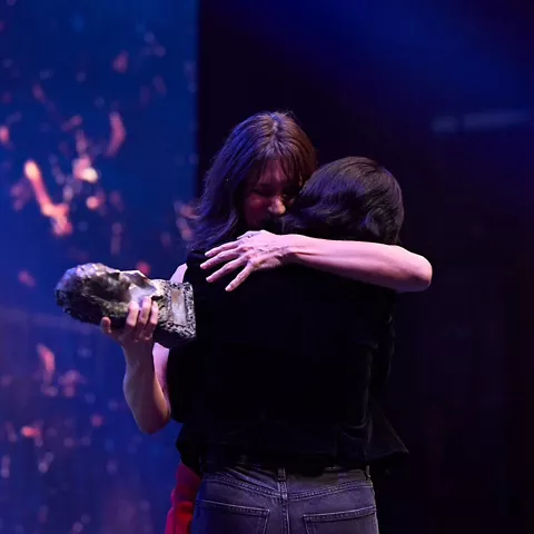 Abrazo en escenario durante entrega de premio