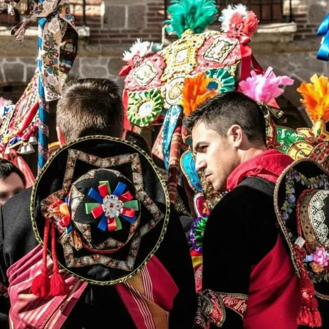 Hombres con vestimenta tradicional y sombreros decorados en celebración.