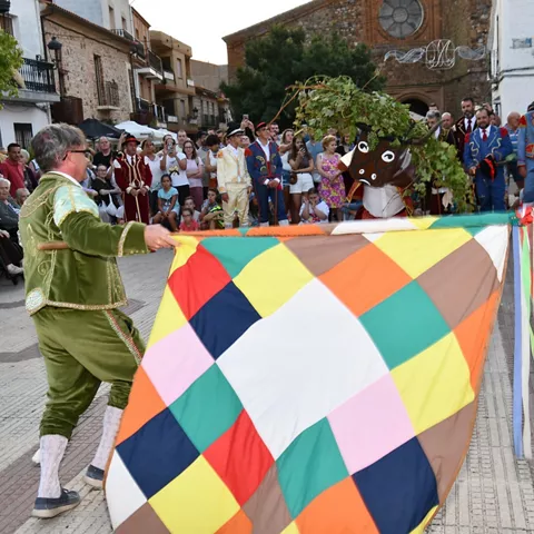 Escena festiva con danza y máscara frente al público