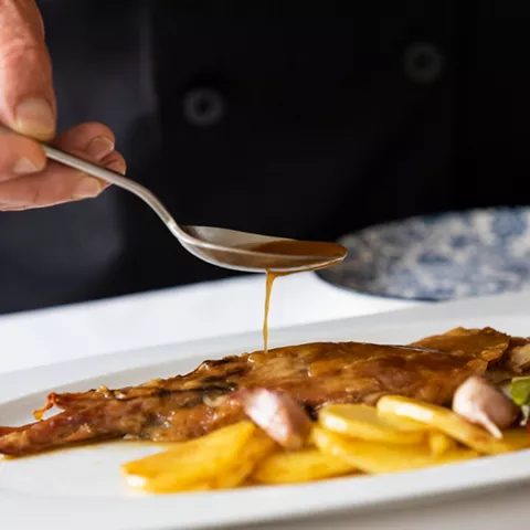 Salsa vertida sobre cordero asado recién emplatado