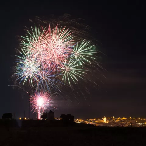 Fuegos artificiales sobre un pueblo de noche.