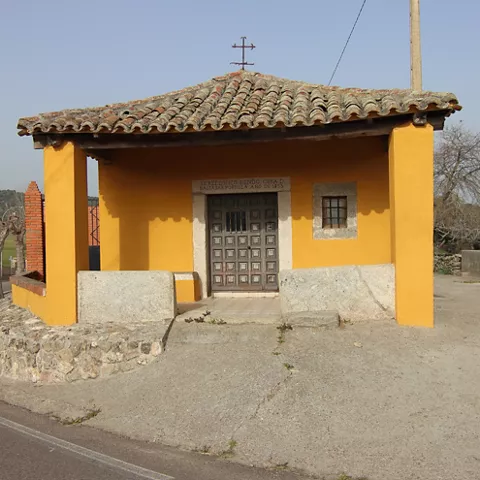 Pequeña ermita amarilla junto a una curva de carretera