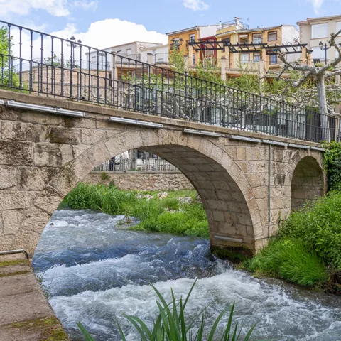 Puente de piedra sobre río urbano.