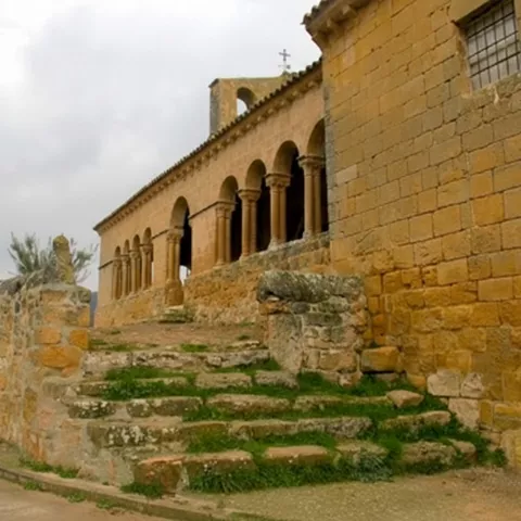 Fachada de piedra con arcos y escalinata.