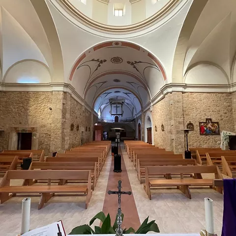 Nave central con bancos de madera y bóveda ornamentada.