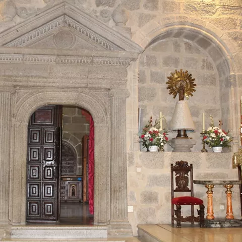Puerta de piedra tallada con acceso a una capilla lateral y elementos litúrgicos.