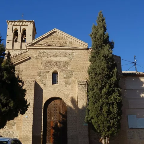 Fachada de iglesia con puerta de madera y torre campanario.