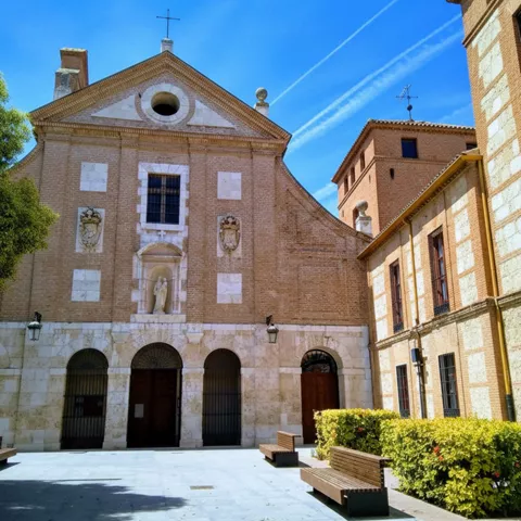 Plaza con iglesia de ladrillo y bancos de madera.