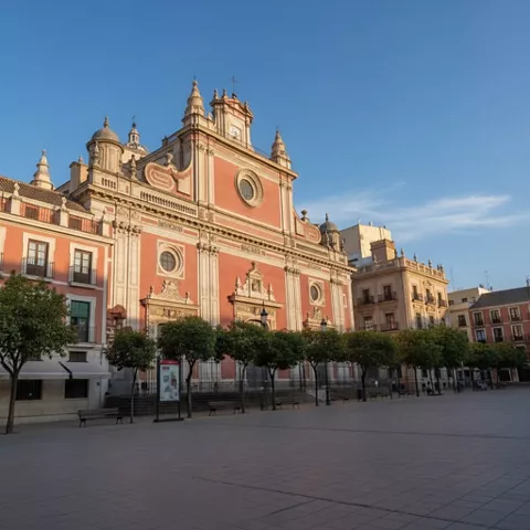 Fachada principal de iglesia con balcones, torres y plaza despejada.