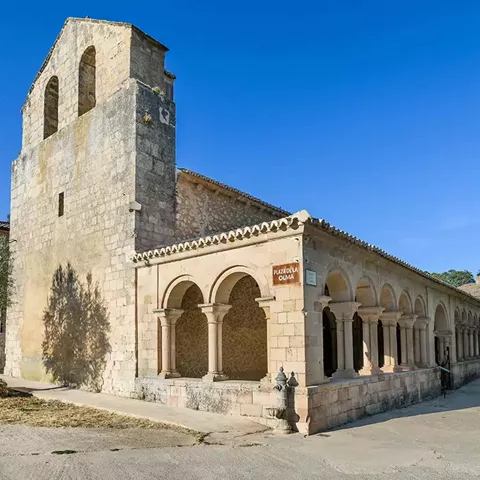 Torre de piedra junto a galería porticada.