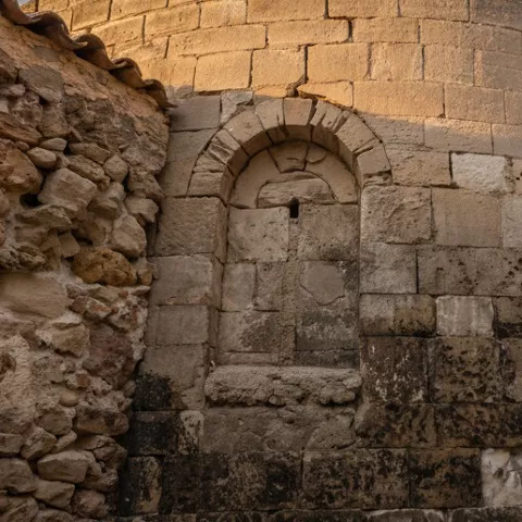 Muro semicircular iluminado con farol antiguo.