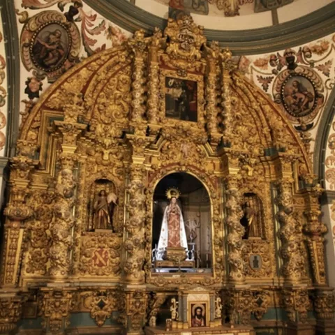 Retablo barroco dorado con tallas y nichos decorados.