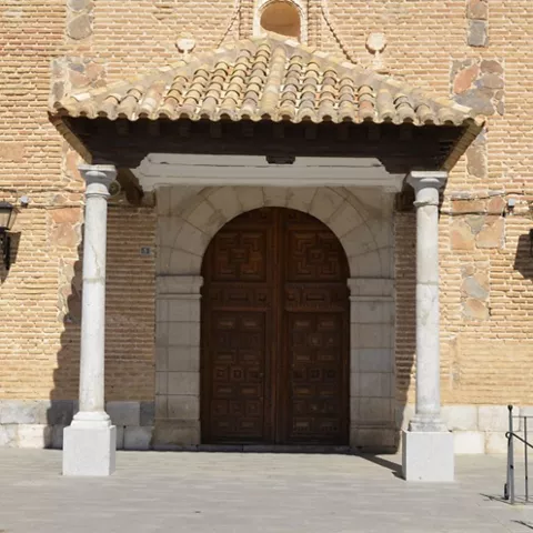 Detalle de entrada con columnas de piedra y puerta de madera tallada.