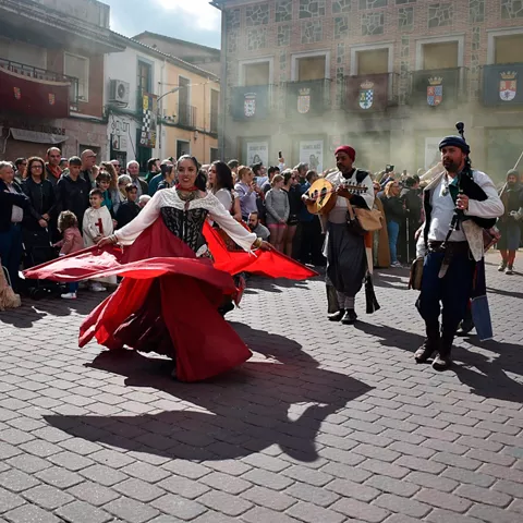 Celebración popular con trajes de época y música en la calle.