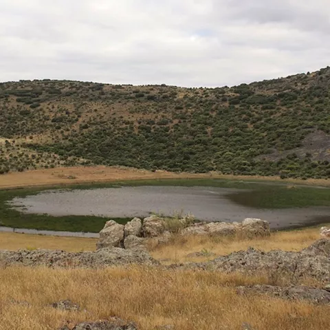 Laguna estacional rodeada de laderas suaves y rocosas.