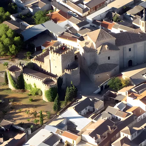 Vista aérea de castillo y gran iglesia entre casas