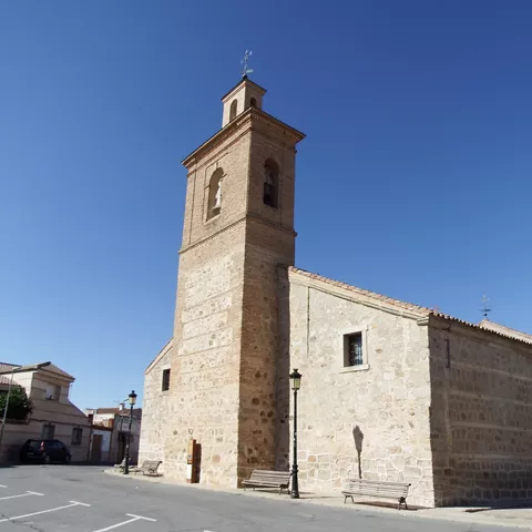 Iglesia de piedra con torre campanario en plaza vacía