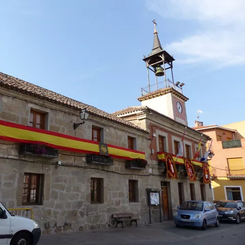 Fachada lateral de ayuntamiento adornada con banderas