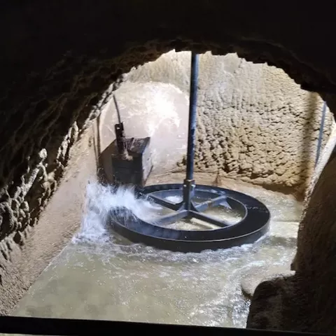 Interior subterráneo con mecanismo circular metálico en una cámara excavada.