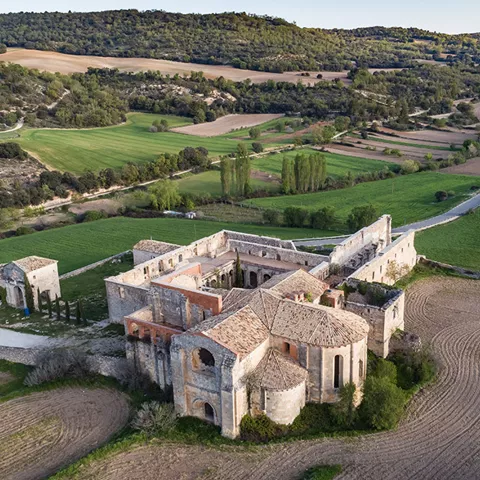 Vista aérea de monasterio entre campos verdes.