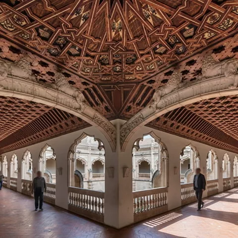 Galería superior con techo artesonado y arcos abiertos al claustro.