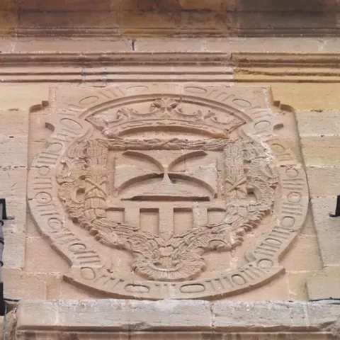 Escudo tallado en piedra sobre fachada histórica.