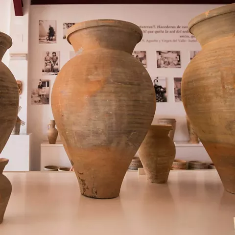 Primer plano de grandes vasijas de barro expuestas en una sala museística.