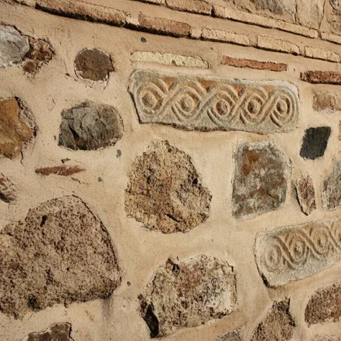 Muro de piedra con relieves decorativos incrustados