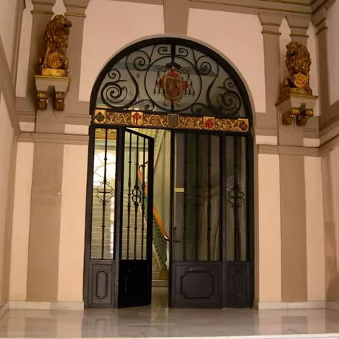 Entrada interior con reja decorativa y elementos arquitectónicos clásicos