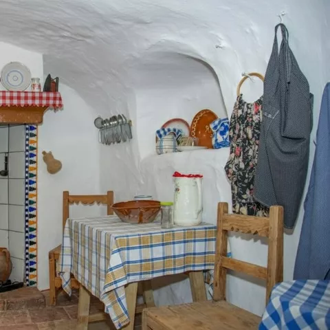 Cocina tradicional con chimenea, mesa pequeña y utensilios antiguos.