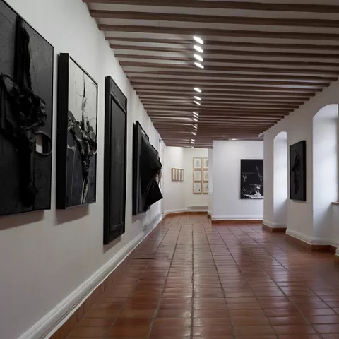 Pasillo con grandes lienzos oscuros y techo de madera.