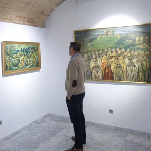 Persona observando tres cuadros en una sala de exposición