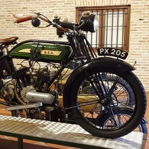 Motocicleta clásica verde expuesta sobre una plataforma en el museo.