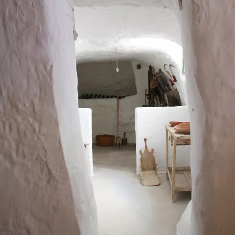 Pasillo de cueva con mesa, cesta y herramientas