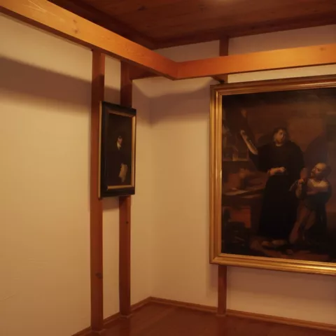 Sala de museo con vigas de madera y pintura enmarcada colgada en la pared.