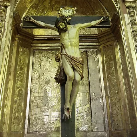 Crucifijo sobre retablo dorado en iglesia histórica