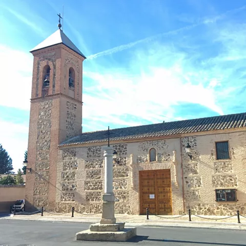 Iglesia de piedra y ladrillo con torre campanario y cruz de piedra