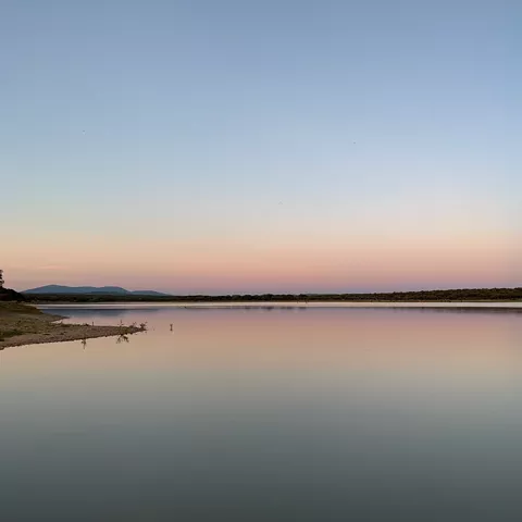 Lago en calma al atardecer con horizonte rosado