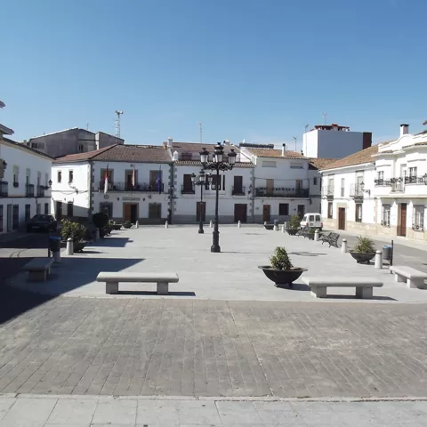 Plaza amplia con farolas, bancos y edificios blancos