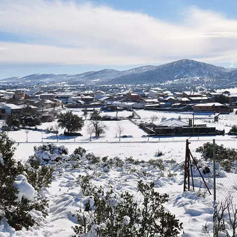 Pueblo cubierto de nieve con montañas al fondo.