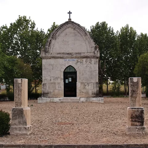 Pequeña ermita de piedra frente a una arboleda    