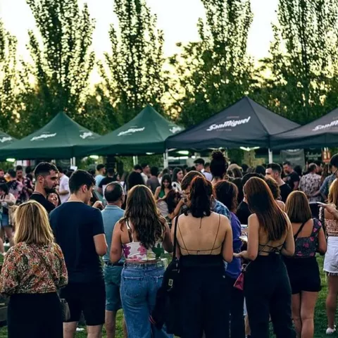 Ambiente de festival con asistentes reunidos junto a carpas al atardecer