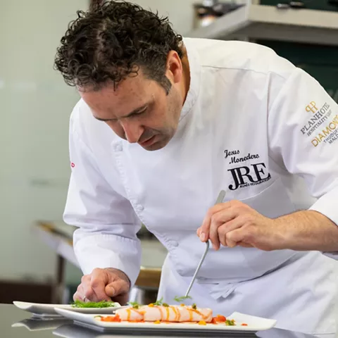 Chef emplatando plato gourmet en cocina profesional