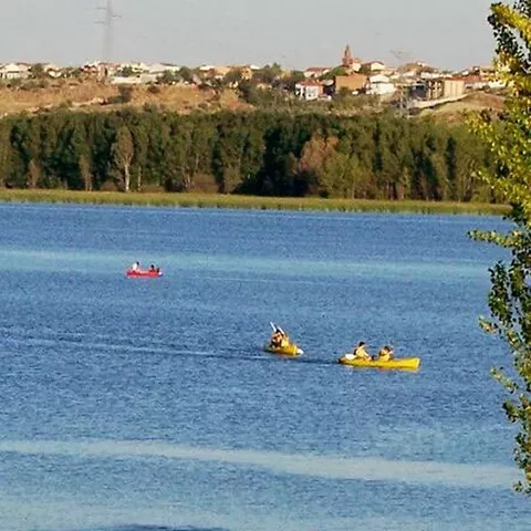 Piraguas navegando en un lago con vegetación y un pueblo al fondo
